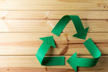 Foto de Primer plano del símbolo de reciclaje de flechas verdes de papel sobre fondo de madera con espacio de copia. Concepto de ecología y reciclaje global. - Imagen libre de derechos