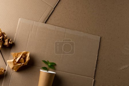 Téléchargez les photos : Gros plan des morceaux de papier et de la tasse avec la plante sur fond de carton avec de l'espace de copie. Concept mondial d'écologie et de recyclage. - en image libre de droit