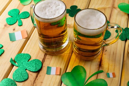 Foto de Imagen de vasos de cerveza, trébol y bandera de Irlanda sobre fondo de madera. Día de San Patricio, tradición irlandesa y concepto de celebración. - Imagen libre de derechos