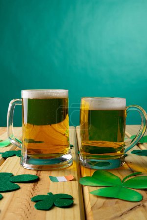 Téléchargez les photos : Image of beer glasses, clover and flag of ireland on wooden background. St patrick's day, irish tradition and celebration concept. - en image libre de droit