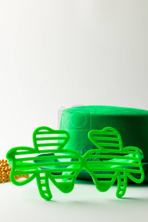 Foto de Imagen de sombrero verde, gafas de trébol verde, collar de oro y espacio de copia sobre fondo blanco. Día de San Patricio, tradición irlandesa y concepto de celebración. - Imagen libre de derechos