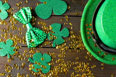 Photo for Image of green hat, green clover, green bow tie and gold sequins on wooden background. St patrick's day, irish tradition and celebration concept. - Royalty Free Image