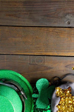 Photo for Image of green hat, green clover, gold sequins and copy space on wooden background. St patrick's day, irish tradition and celebration concept. - Royalty Free Image