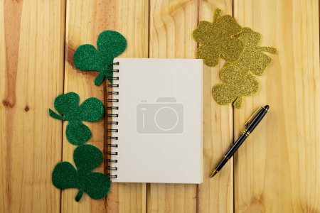 Foto de Imagen de trébol verde y papel blanco con espacio de copia sobre fondo de madera. Día de San Patricio, tradición irlandesa y concepto de celebración. - Imagen libre de derechos