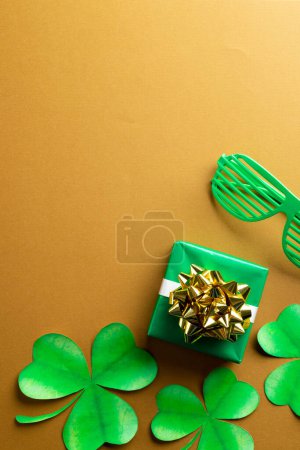 Photo for Image of green glasses, green clover, green present and copy space on orange background. St patrick's day, irish tradition and celebration concept. - Royalty Free Image