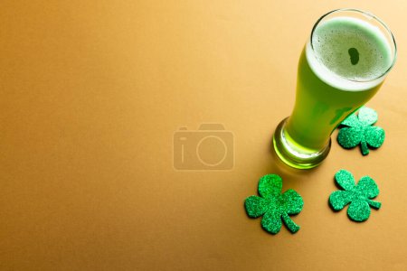 Photo for Image of glass with green beer, clover and copy space on orange background. St patrick's day, irish tradition and celebration concept. - Royalty Free Image