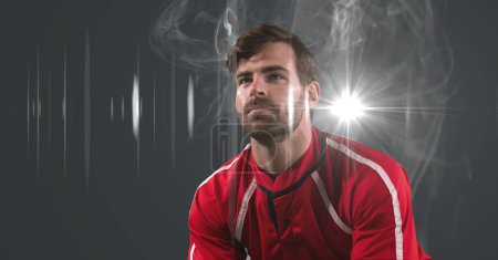 Foto de Atleta masculino caucásico contra el efecto del humo y la mancha de luz sobre fondo gris. torneo deportivo y concepto de competición - Imagen libre de derechos