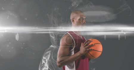 Photo for African american male basketball player holding ball against smoke effect on grey background. sports tournament and competition concept - Royalty Free Image