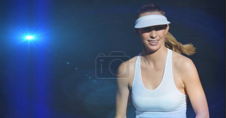 Foto de Jugadora de tenis caucásica contra mancha brillante de luz sobre fondo azul. torneo deportivo y concepto de competición - Imagen libre de derechos