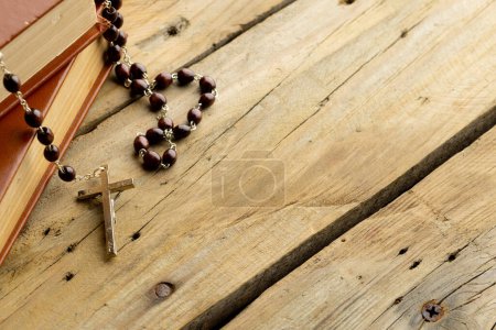 Image of close up of two holy bibles with rosary and copy space on wooden background. Easter, religion, tradition and celebration concept.