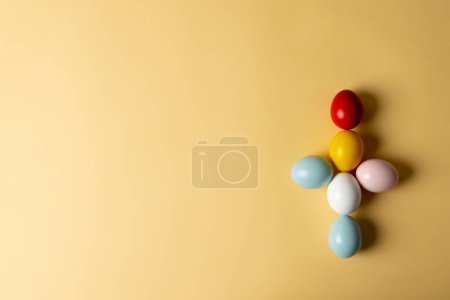 Téléchargez les photos : Image d'œufs de Pâques multicolores formant une croix avec espace de copie sur fond jaune. Pâques, religion, tradition et concept de célébration. - en image libre de droit