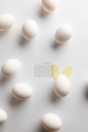 Téléchargez les photos : Image d'œufs de Pâques blancs avec des oreilles de lapin et un espace de copie sur fond blanc. Pâques, religion, tradition et concept de célébration. - en image libre de droit