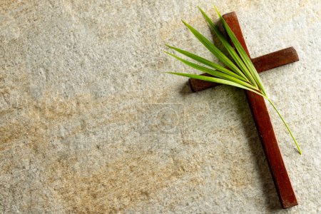 Image of close up of cross with palm leaf and copy space on stone background. Easter, religion, tradition and celebration concept.