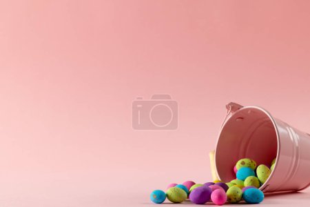 Téléchargez les photos : Image d'oeufs de Pâques multicolores, seau rose avec espace de copie sur fond rose. Pâques, religion, tradition et concept de célébration. - en image libre de droit