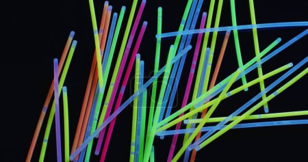 Téléchargez les photos : Image de plusieurs bâtons lumineux néon colorés sur fond noir. Contexte, copyspace et concept de couleurs. - en image libre de droit