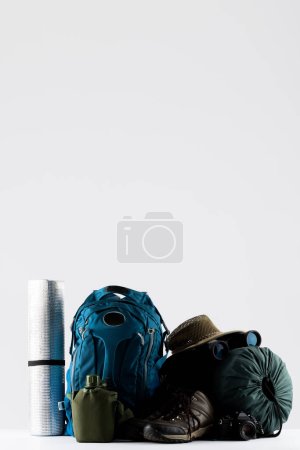 Photo for Close up of blue backpack, mat, trekking sticks and sleeping bag on white background with copy space. National camping month, equipment and celebration concept. - Royalty Free Image