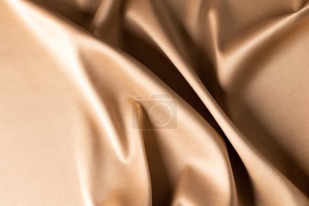 Foto de Primer plano de tela de satén beige liso con pliegues, espacio de copia. Color, textura y material. - Imagen libre de derechos