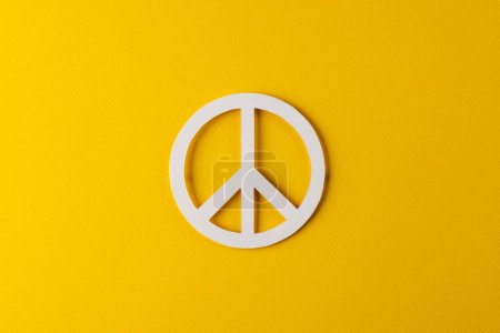 Téléchargez les photos : Vue grand angle de signe de paix blanc avec espace de copie sur fond jaune. Concept de mouvement pour la paix et contre la guerre. - en image libre de droit
