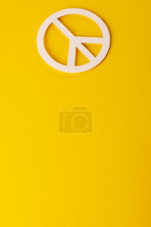 Foto de Vista de ángulo alto del signo de paz blanco con espacio de copia sobre fondo amarillo. Concepto de paz y movimiento contra la guerra. - Imagen libre de derechos
