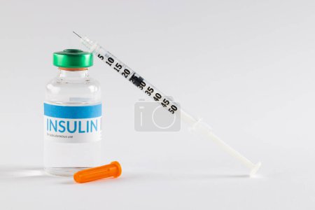 Insulina en vial y jeringa sin tapar sobre fondo blanco. Azúcar en sangre, diabetes y conciencia de salud.