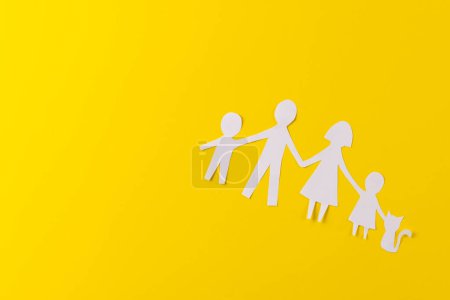 Téléchargez les photos : Livre blanc découpé de la famille avec deux enfants et ca et copier l'espace sur fond jaune. Aide humanitaire, personnes, aide et concept humain. - en image libre de droit