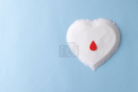 Photo for Blood drop over sugar in heart shape on blue background with copy space. Diet, blood sugar, diabetes and heart health awareness. - Royalty Free Image