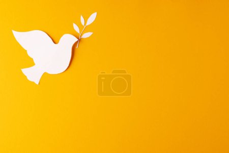 Photo for Close up of white dove with leaf and copy space on yellow background. Peace and anti war movement concept. - Royalty Free Image