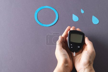 Photo for Hands of caucasian woman holding glucometer over blue drops and ring on grey background, copy space. Blood sugar, diabetes and health awareness. - Royalty Free Image