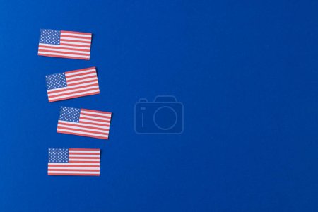 Téléchargez les photos : Vue en angle élevé de quatre drapeaux des États-Unis d'Amérique avec espace de copie sur fond bleu. Patriotisme américain, fête de l'indépendance et concept de tradition. - en image libre de droit