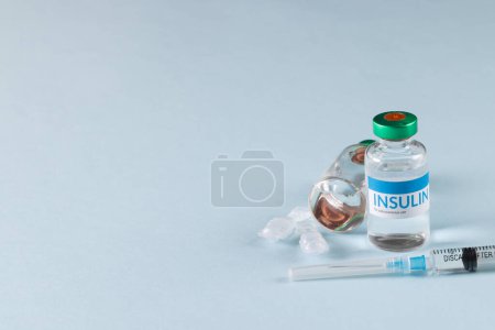 Photo for Vials of insulin with caplets and syringe on blue background with copy space. Blood sugar, diabetes, treatment and health awareness. - Royalty Free Image