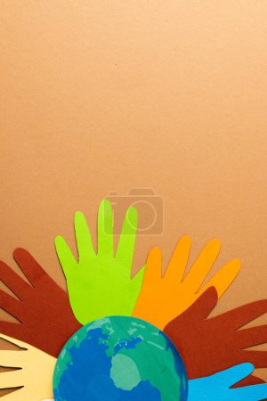 Foto de Papel cortado de manos multicolores y globo con espacio de copia sobre fondo marrón. Ayuda humanitaria, personas, ayuda y concepto humano. - Imagen libre de derechos
