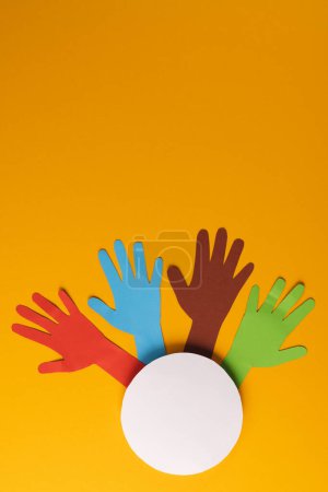 Photo for Paper cut out of multi coloured hands and white circle with copy space on orange background. Humanitarian aid, people, help and human concept. - Royalty Free Image