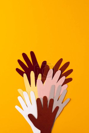 Photo for Paper cut out of multi coloured hands with copy space on orange background. Humanitarian aid, people, help and human concept. - Royalty Free Image