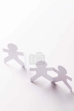 Photo for Close up of four paper cut out people figures holding hands with copy space on white background. Humanitarian, people, help and human concept. - Royalty Free Image
