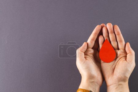 Téléchargez les photos : Mains de femme caucasienne coupant goutte de sang, sur fond gris avec espace de copie. Don de sang, médicaments et soins de santé. - en image libre de droit