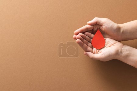 Photo for Hands of caucasian woman cupping blood drop, on brown background with copy space. Blood donation, medicine and healthcare. - Royalty Free Image