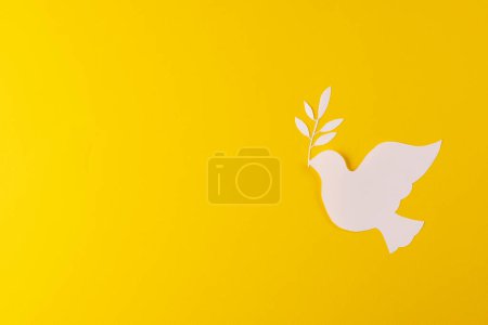 Photo for Close up of white dove with leaf and copy space on yellow background. Peace and anti war movement concept. - Royalty Free Image