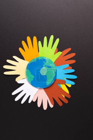 Photo for Paper cut out of multi coloured hands and globe with copy space on black background. Humanitarian aid, people, help and human concept. - Royalty Free Image