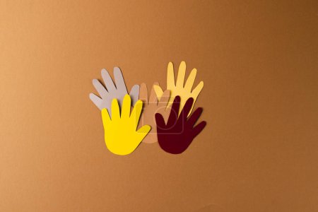 Photo for Paper cut out of multi coloured hands with copy space on brown background. Humanitarian aid, people, help and human concept. - Royalty Free Image
