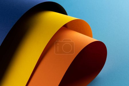 Téléchargez les photos : Gros plan de papier bleu marine, jaune et orange sur fond bleu. Couleur, texture et matériau. - en image libre de droit