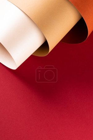 Téléchargez les photos : Gros plan de papier orange, beige et blanc sur fond rouge avec espace de copie. Couleur, texture et matériau. - en image libre de droit