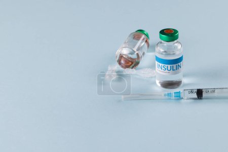 Téléchargez les photos : Flacons d'insuline avec caplets et seringue sur fond bleu avec espace de copie. Glycémie, diabète, traitement et sensibilisation à la santé. - en image libre de droit
