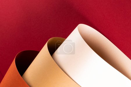 Foto de Primer plano de papel naranja, beige y blanco sobre fondo rojo con espacio para copiar. Color, textura y material. - Imagen libre de derechos