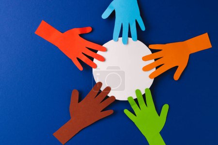 Foto de Papel cortado de manos multicolores y círculo blanco con espacio de copia sobre fondo azul. Humanitario, pueblo, ayuda y concepto humano. - Imagen libre de derechos