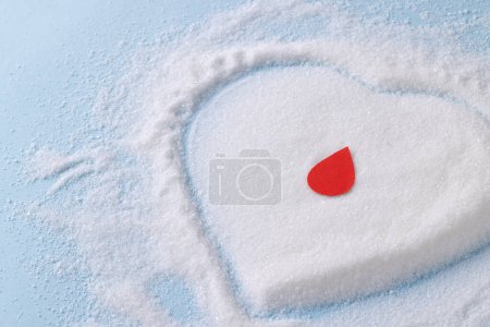 Photo for Blood drop over sugar in heart shape on blue background. Diet, blood sugar, diabetes and heart health awareness. - Royalty Free Image