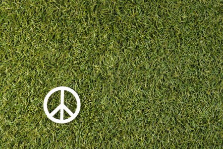 Foto de Vista de ángulo alto del signo de paz blanco con espacio de copia en el fondo de hierba. Concepto de paz y movimiento contra la guerra. - Imagen libre de derechos