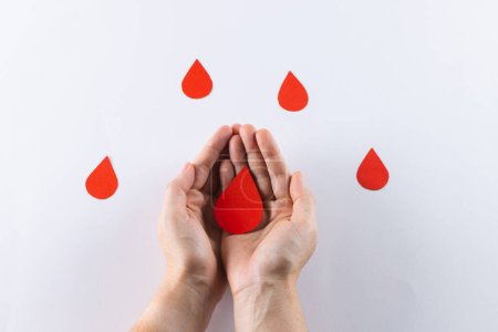 Photo for Hands of caucasian woman cupping blood drop, with blood drops on white background. Blood donation, medicine and healthcare. - Royalty Free Image