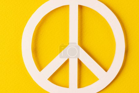 Téléchargez les photos : Vue grand angle de signe de paix blanc avec espace de copie sur fond jaune. Concept de mouvement pour la paix et contre la guerre. - en image libre de droit