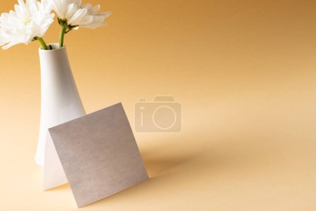 Photo for Image of white flowers in white vase and card with copy space on yellow background. Mothers day, nature and spring concept. - Royalty Free Image