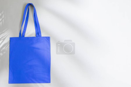 Téléchargez les photos : Vue grand angle du sac en toile bleue avec espace de copie et ombre sur fond gris. Sacs et concept de mode. - en image libre de droit